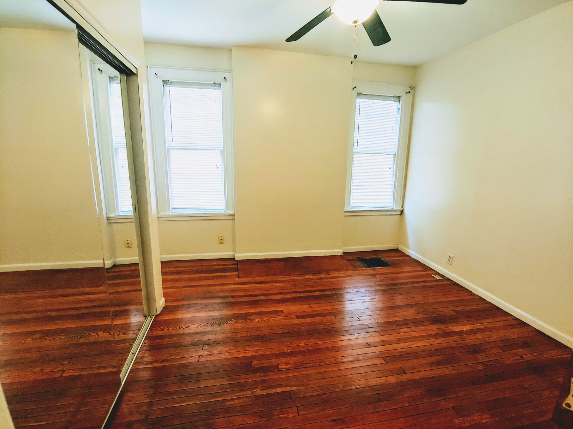 1818 Summit St. bedroom with mirrored closet doors, two bright windows, and hardwood floors