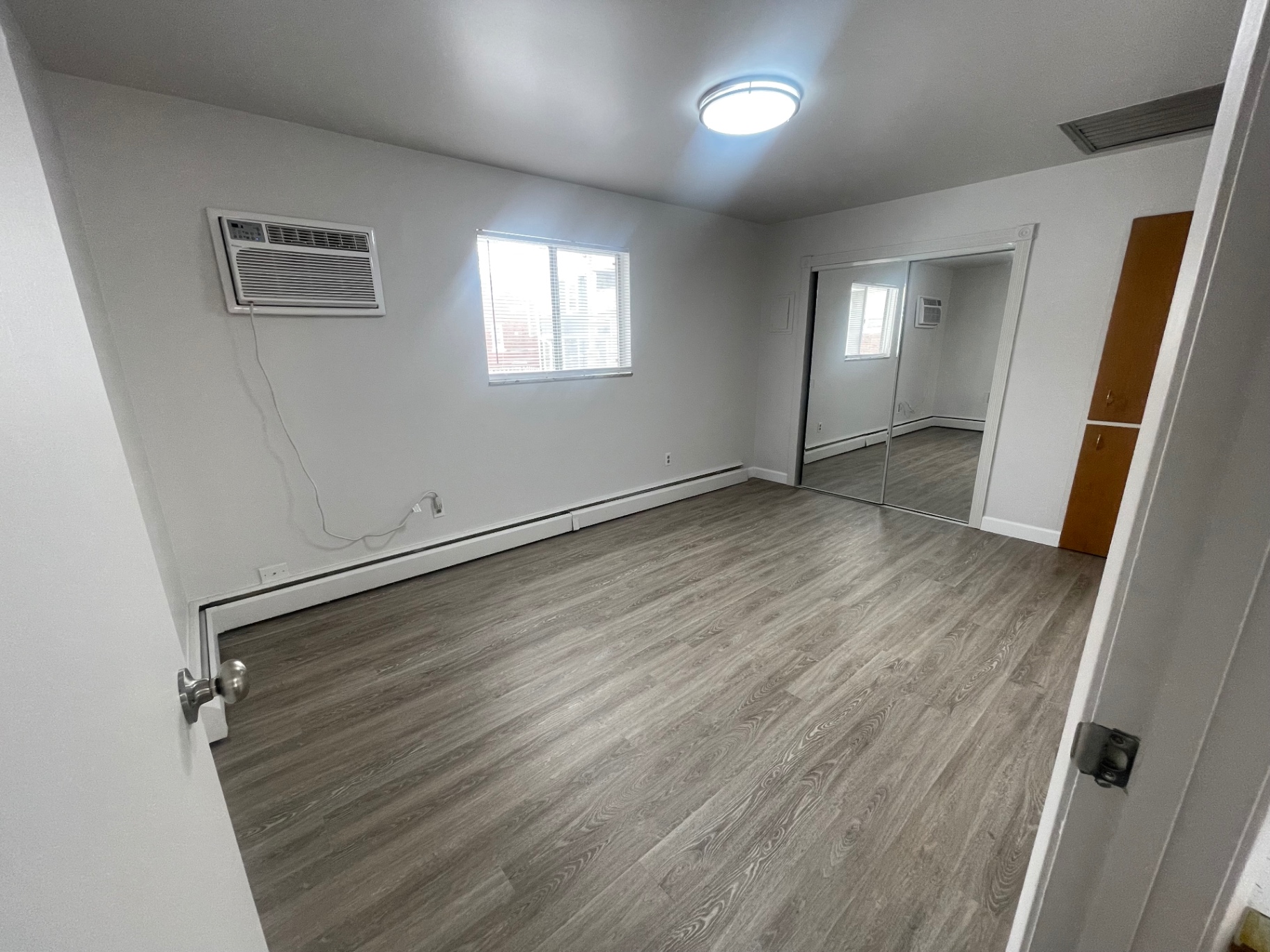1827 N 4th St. Unit 8 bedroom with mirrored closet doors, window AC, and wood-look flooring