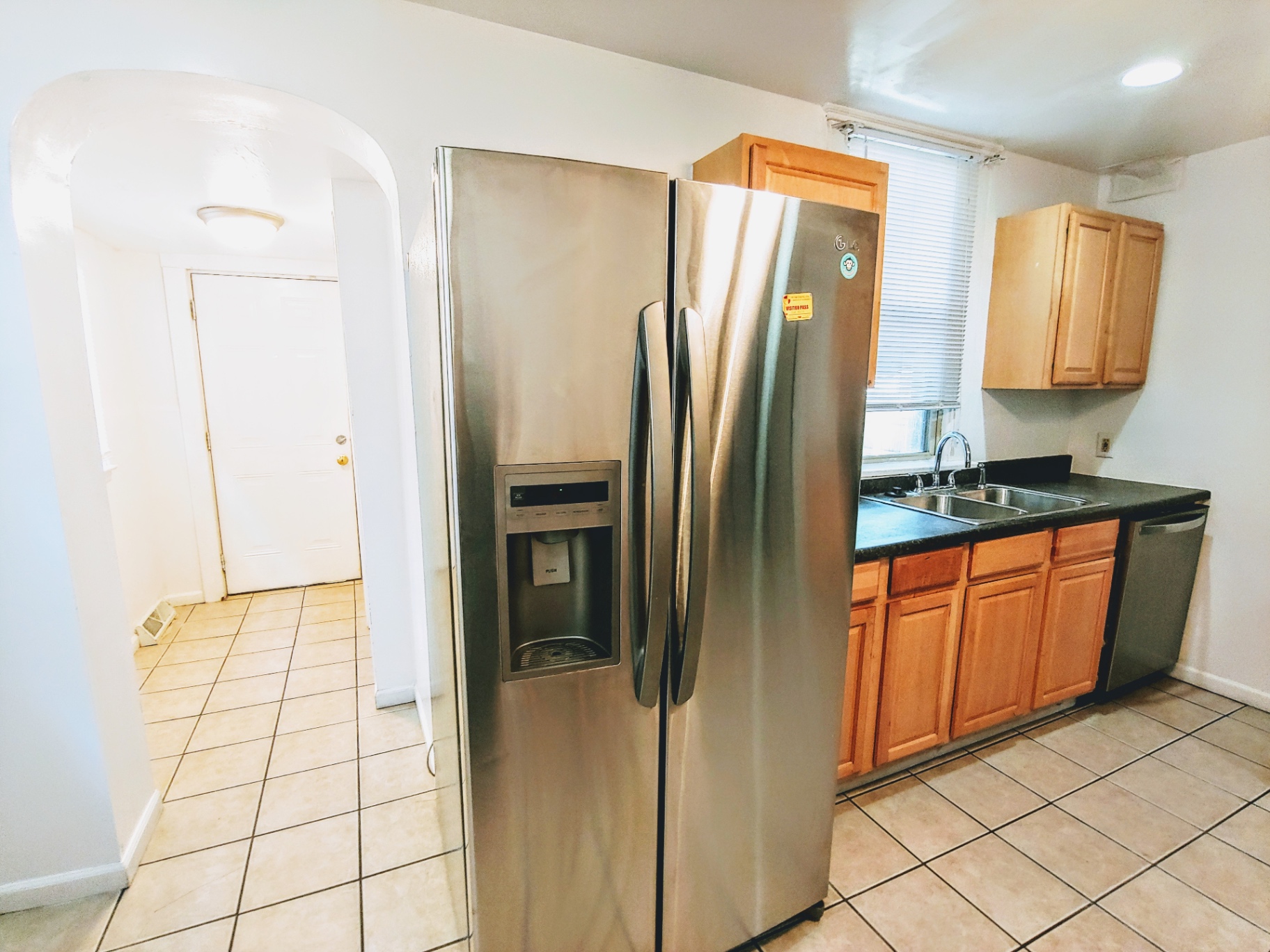 1818 Summit St. kitchen with stainless side-by-side fridge, dishwasher, and archway to mudroom