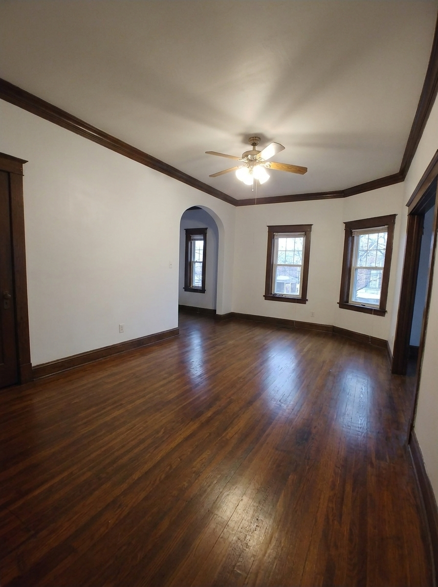 Unit C large living room with hardwood floors and three front windows