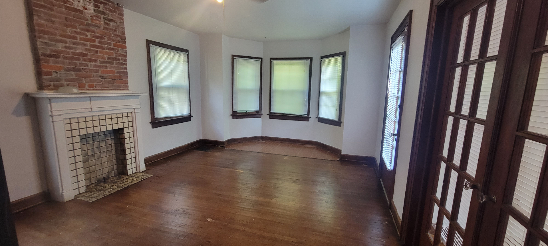 2044 Iuka Ave. C living room with decorative tiled fireplace, exposed brick chimney, and bay-style window alcove