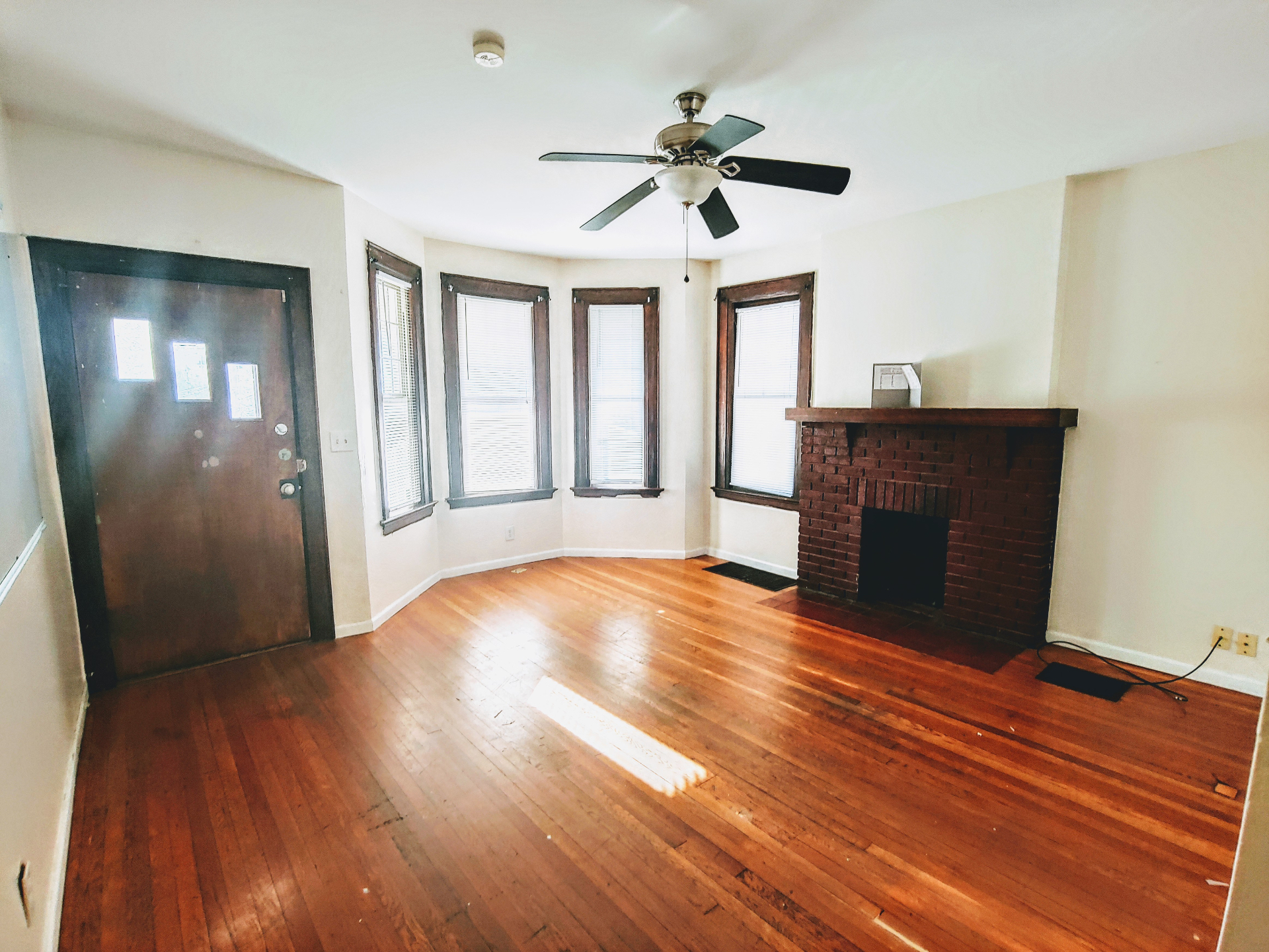 1818 Summit St. living room with bay windows, red brick fireplace, ceiling fan, and hardwood floors