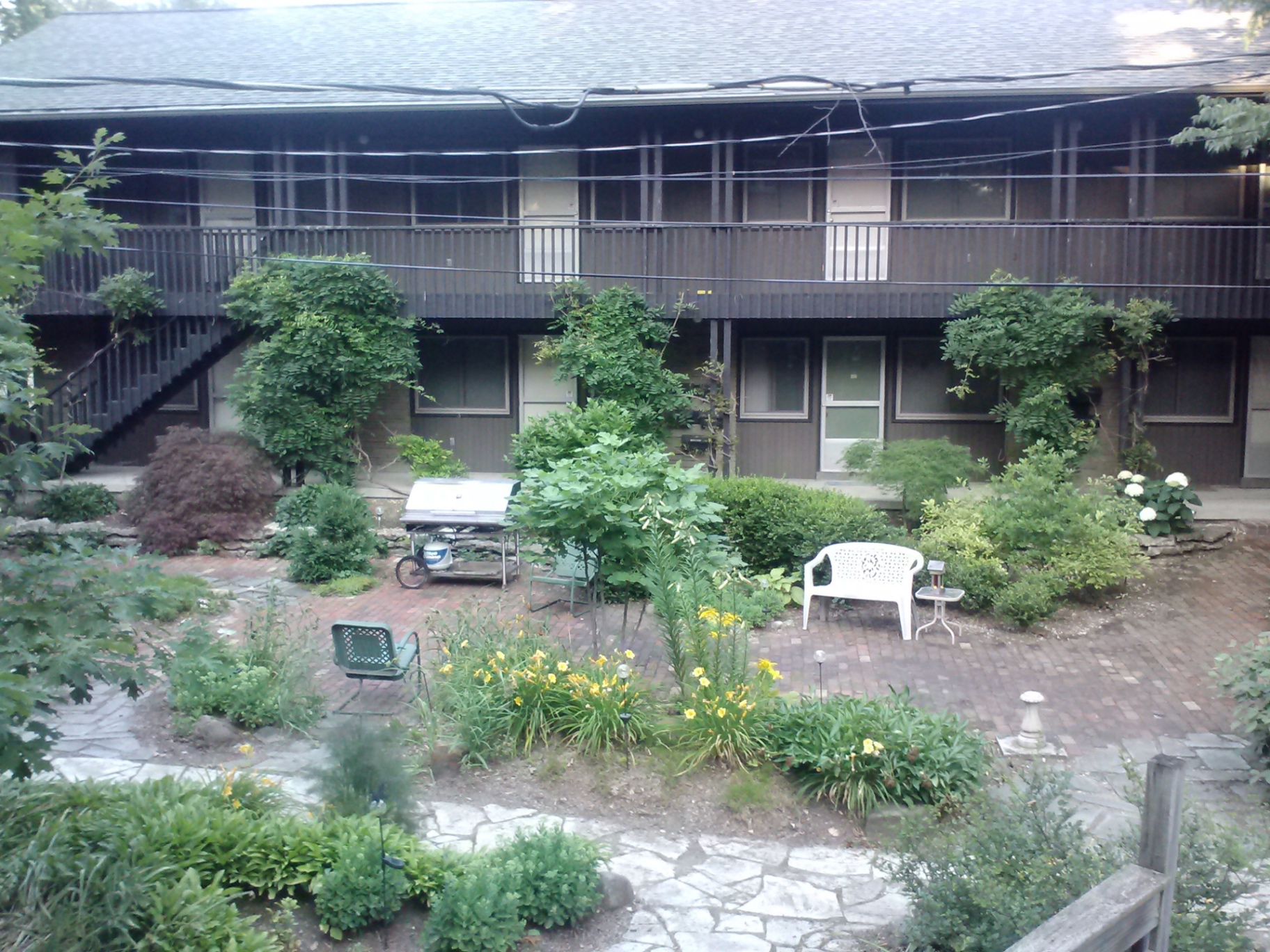2040 Iuka Ave. 4B lush shared courtyard with brick patio, mature landscaping, and two-story building