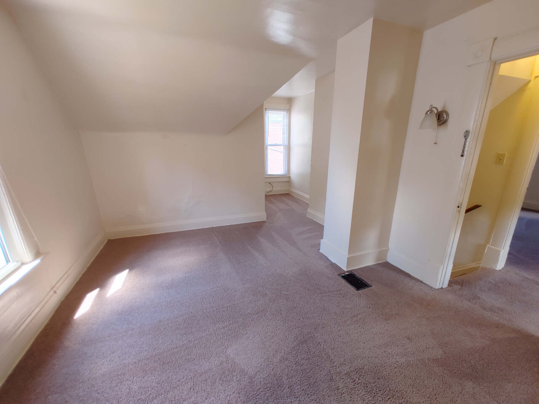 Rear unit upstairs bedroom with sconce, dormer nook and two windows