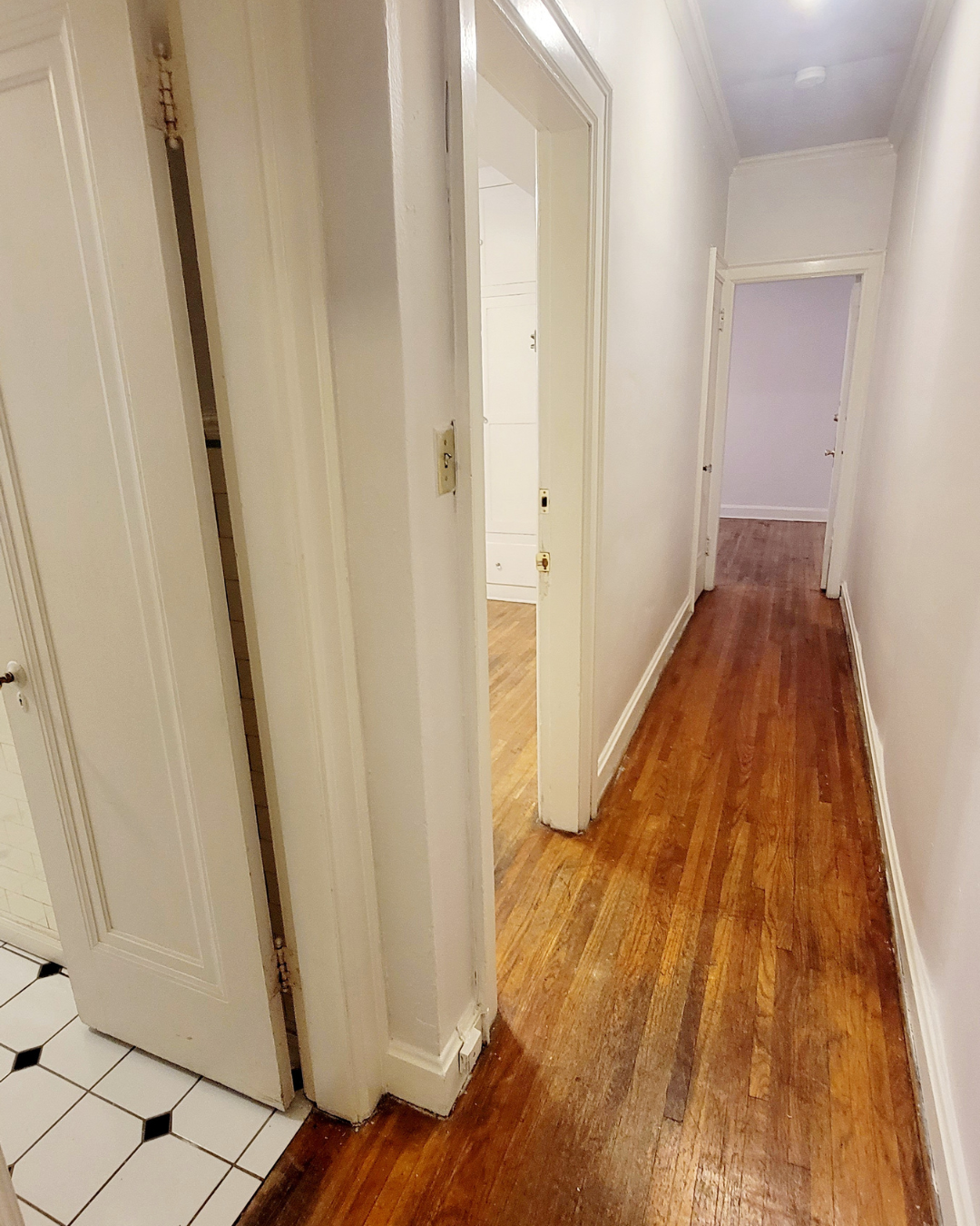 Unit A long interior hallway with hardwood floors and multiple room entries