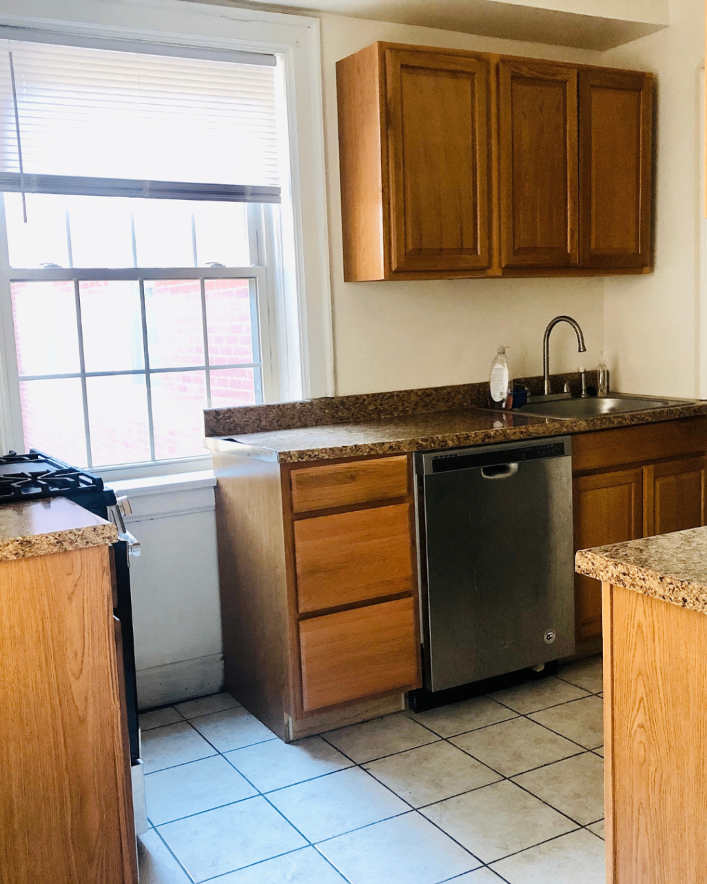 Unit A kitchen with granite countertops, stainless dishwasher, and large window