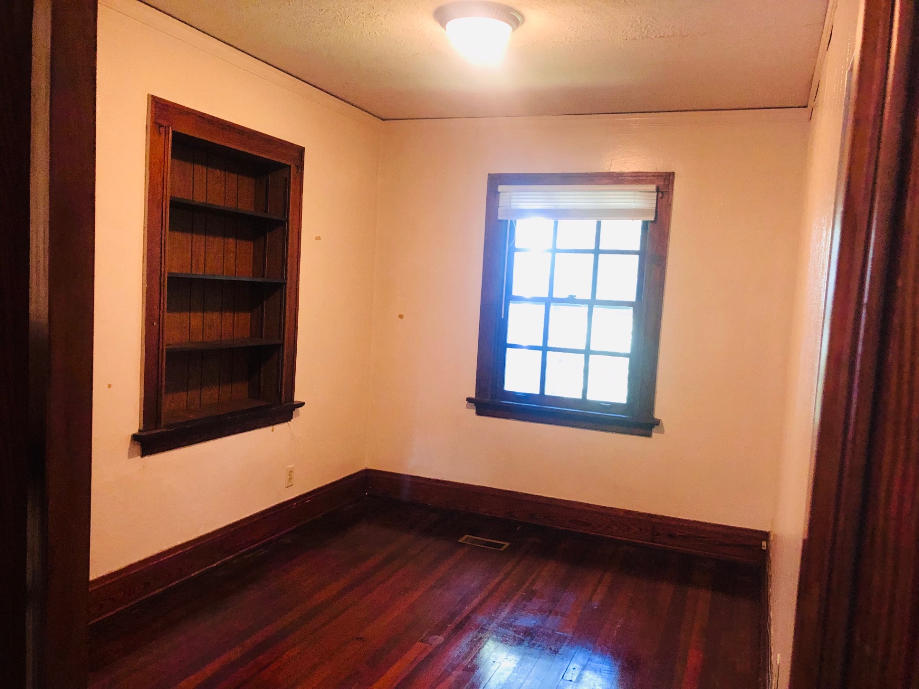 2026 Iuka Ave C room with built-in wood shelving and refinished hardwood floors