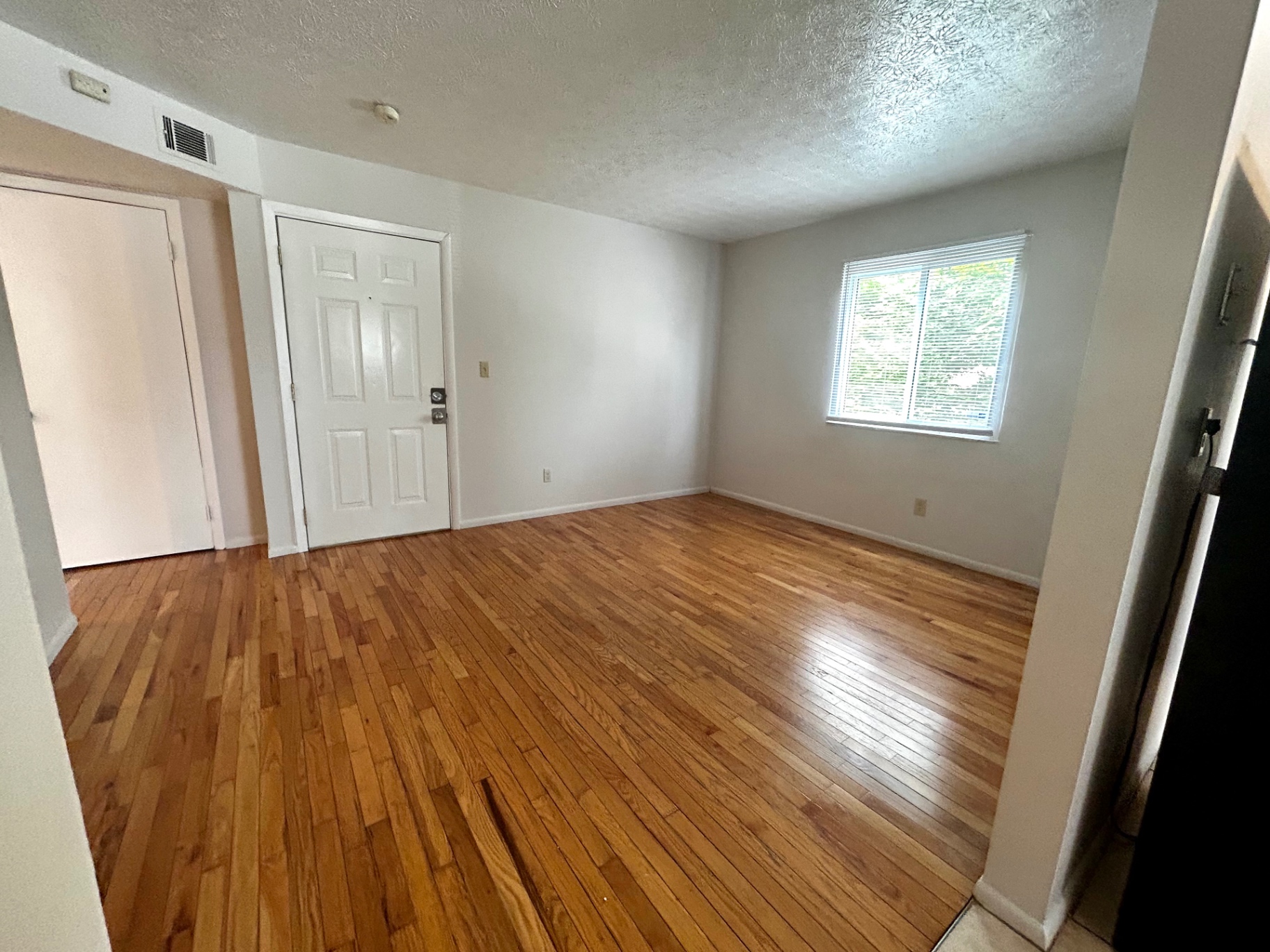 2150 N 4th St. Unit C living room with refinished hardwood floors, bright window, and front entry