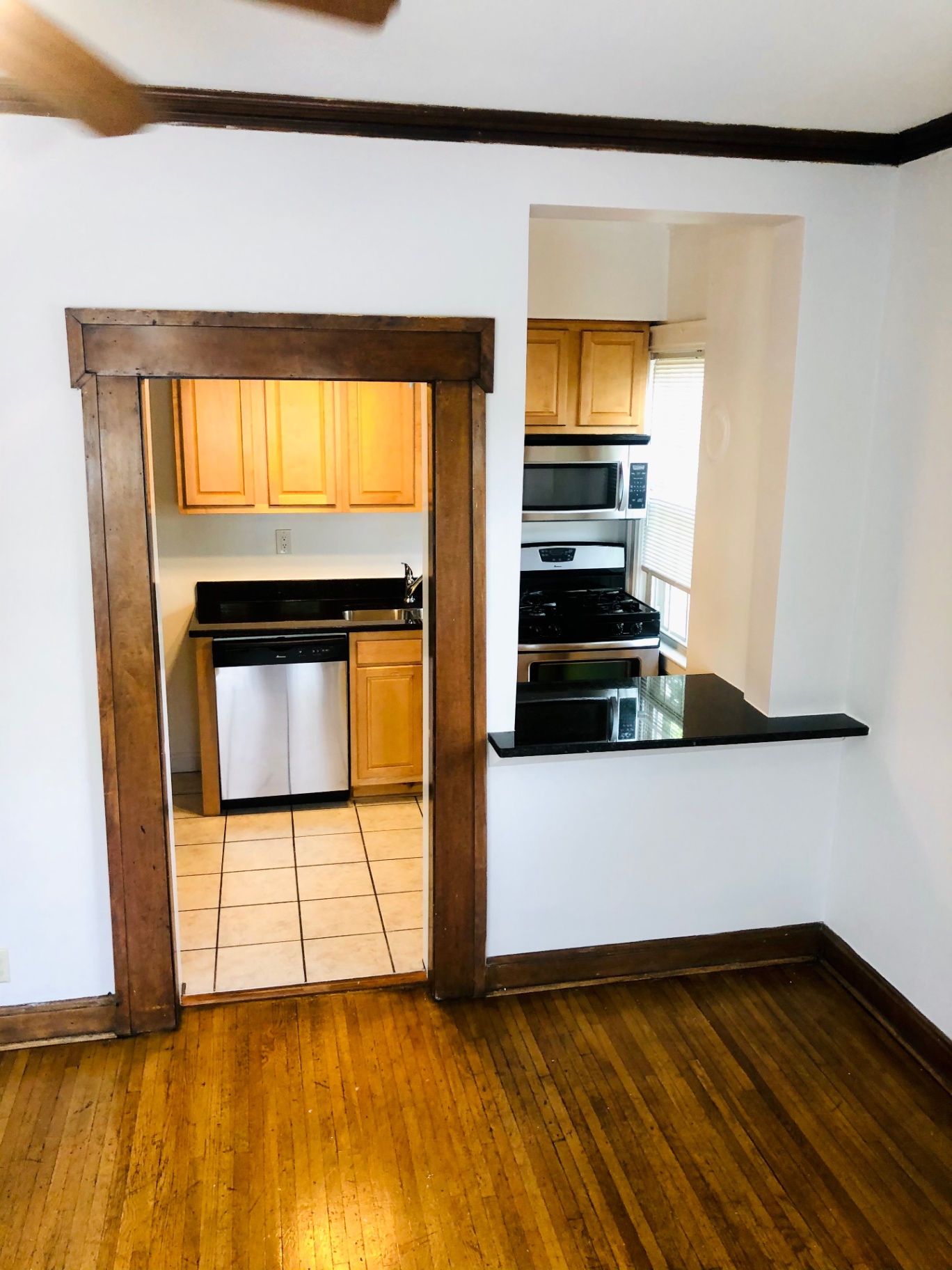 Unit L kitchen entryway with stainless dishwasher and granite pass-through