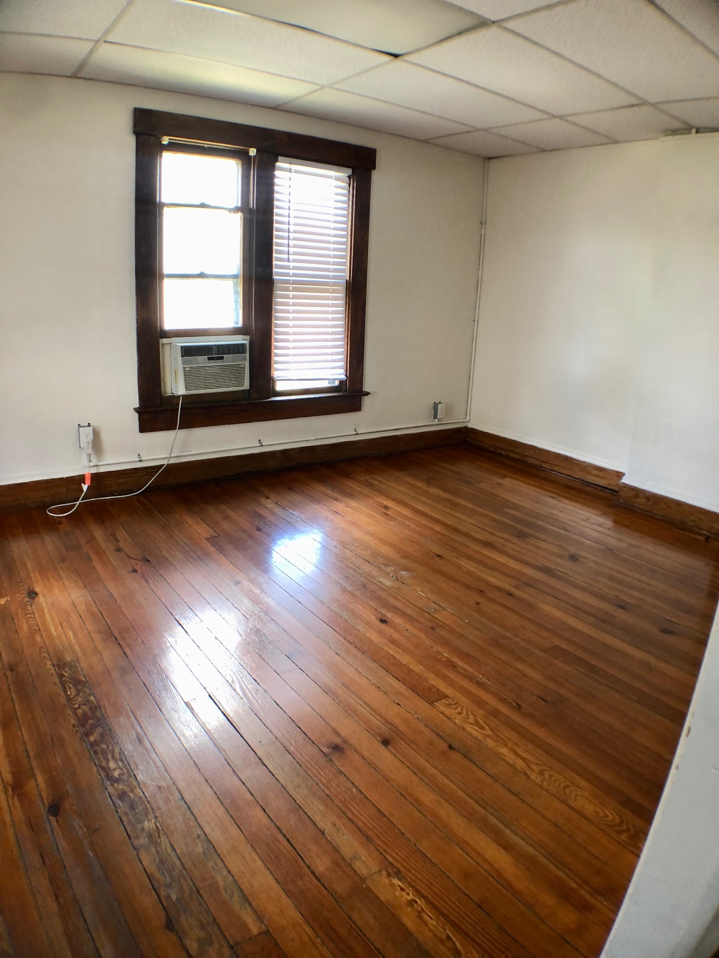 89 E Woodruff Ave. Unit A bedroom with refinished hardwood floors, tall window, and window AC unit