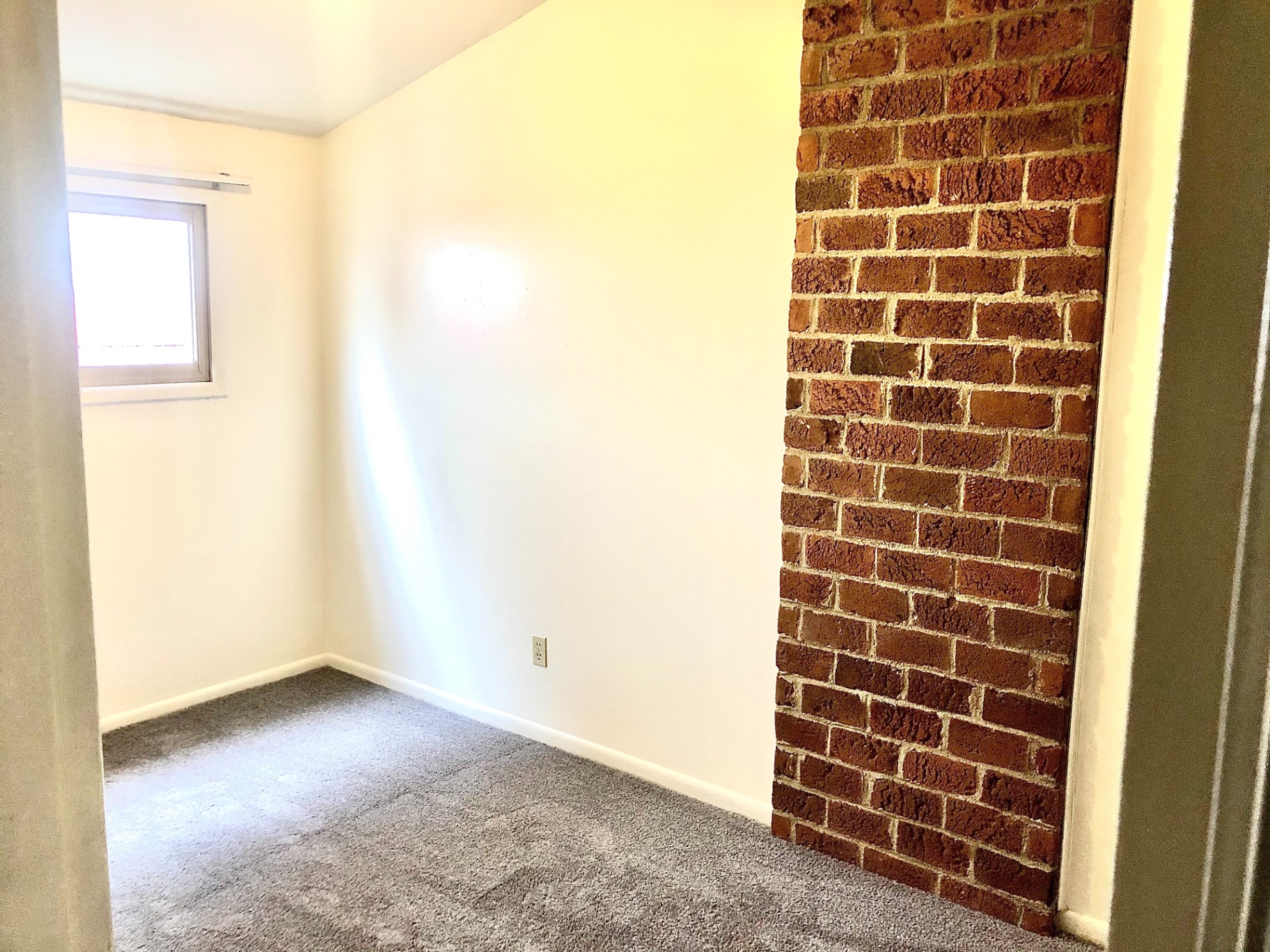 2011 Summit St. Unit C carpeted bedroom with exposed brick accent wall