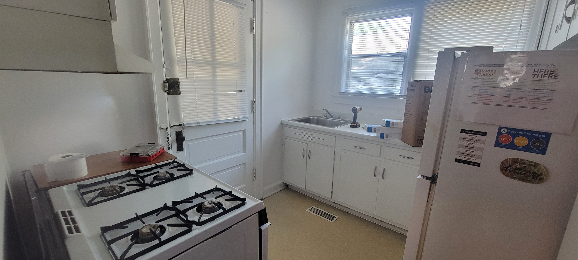 2044 Iuka Ave. C kitchen with gas range, white cabinetry, refrigerator, and rear exterior door