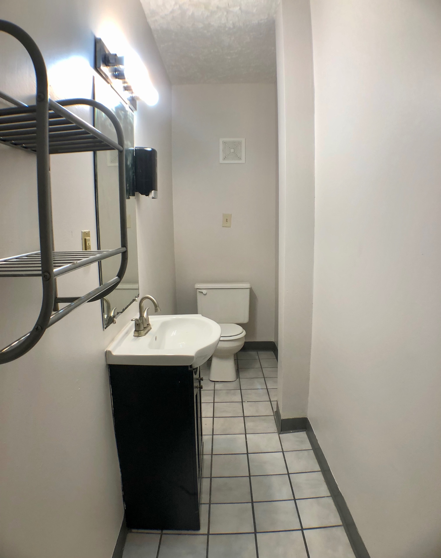 Unit A bathroom with tile floor, black vanity and pedestal-style sink