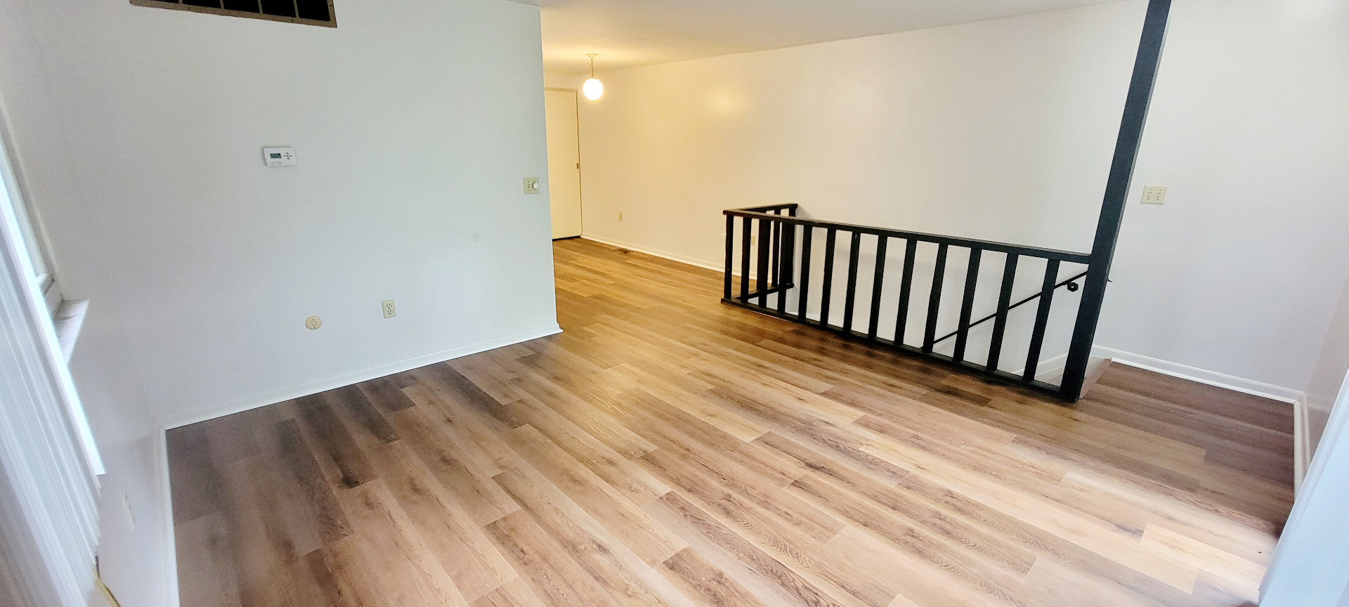 2024 Summit St. open main living area with plank floors, stair rail, and bright white walls