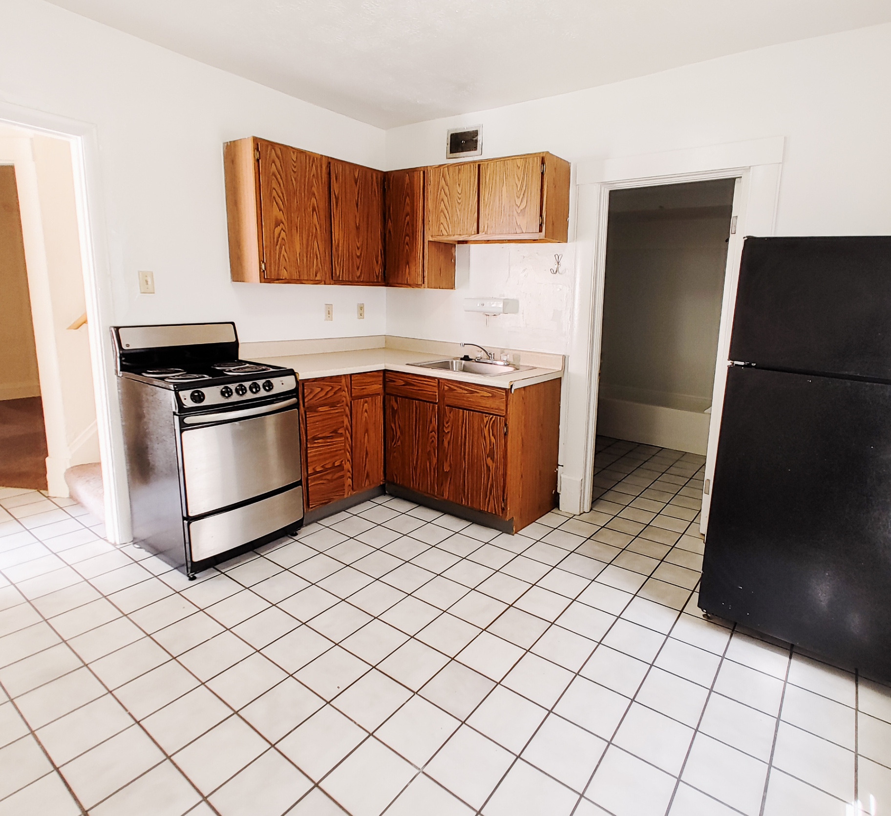 Rear unit kitchen with wood cabinets, stainless-front range and tile floor