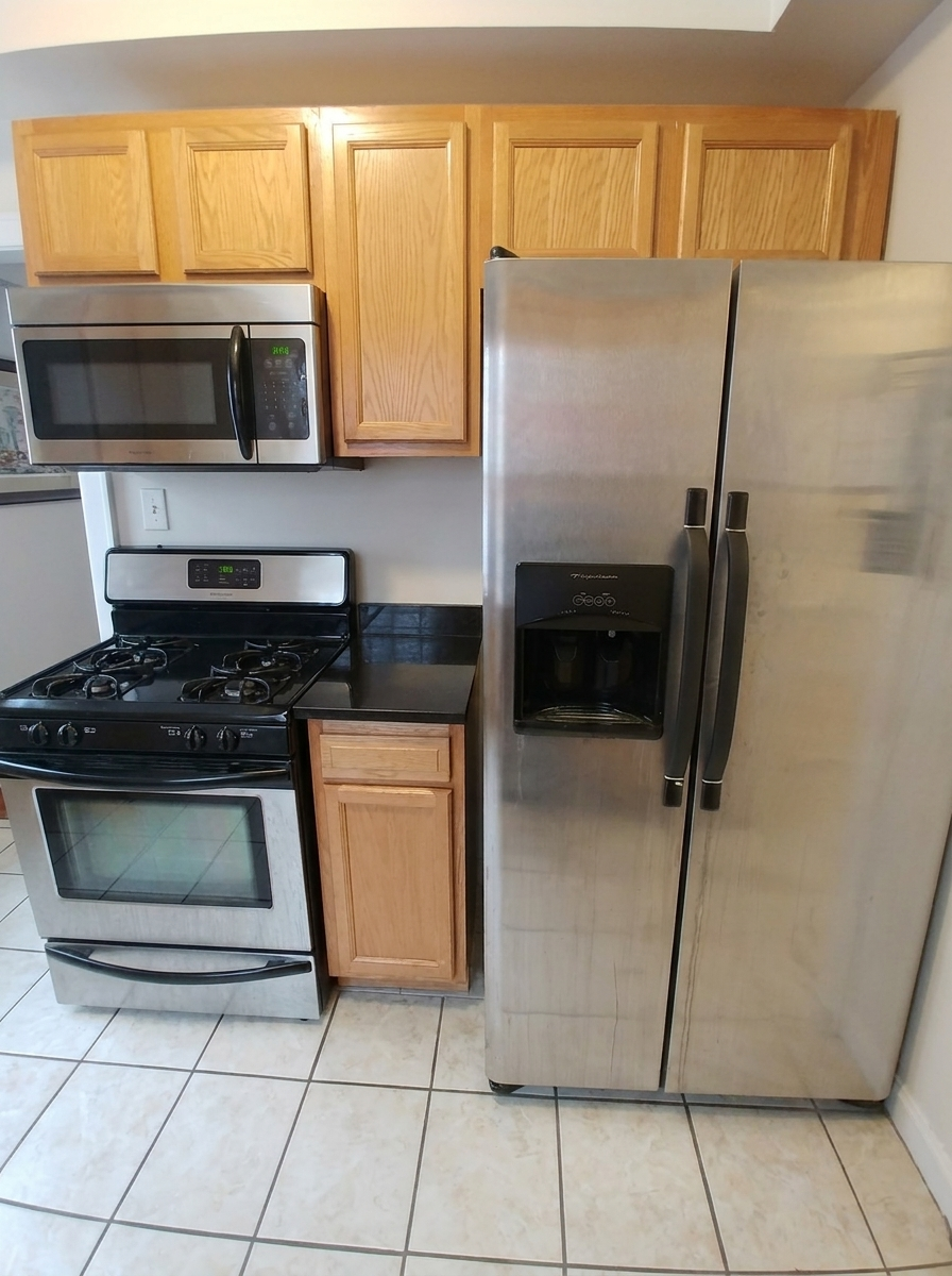 Unit C kitchen close-up with stainless steel refrigerator, microwave, and range