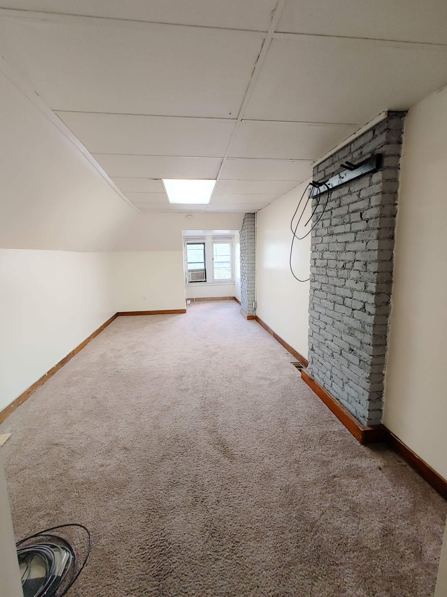 89 E Woodruff Ave. Unit C spacious carpeted living room with exposed painted brick chimney and natural light