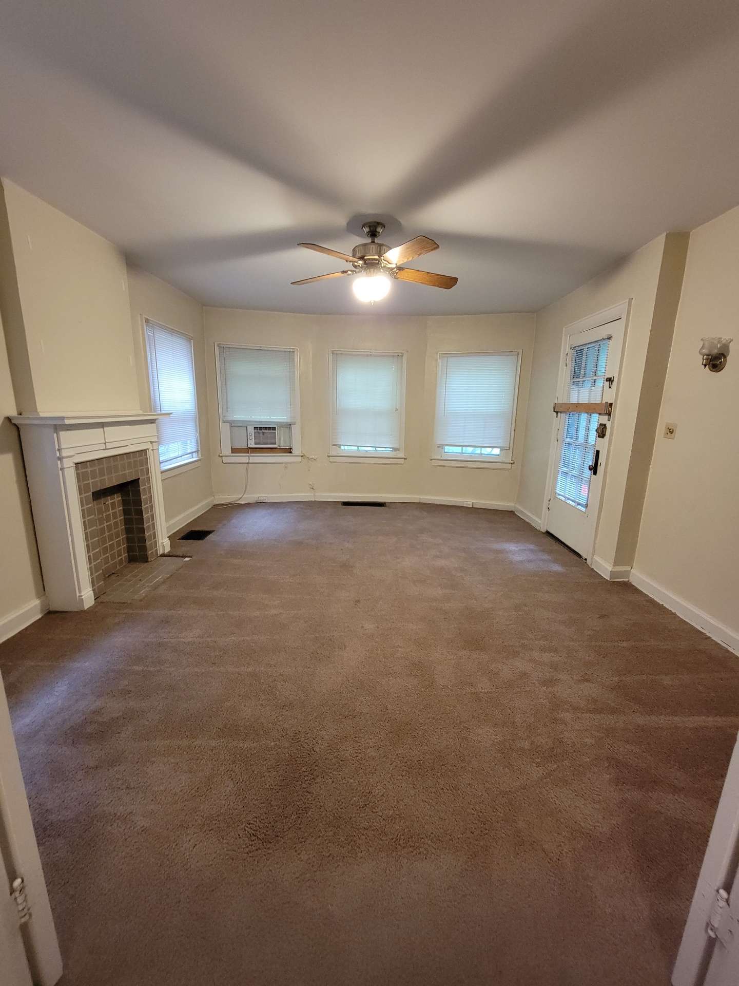 2048 Iuka Ave. B living room angle showing tile fireplace and rear entry door