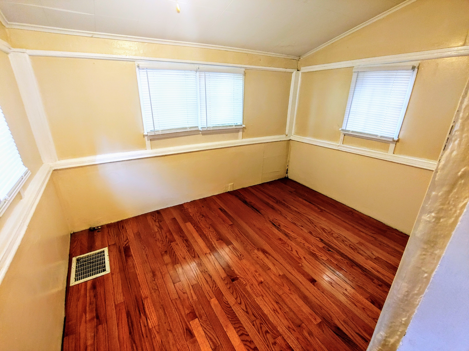 1818 Summit St. bedroom with refinished red-oak hardwood floors, vaulted ceiling, and multiple windows