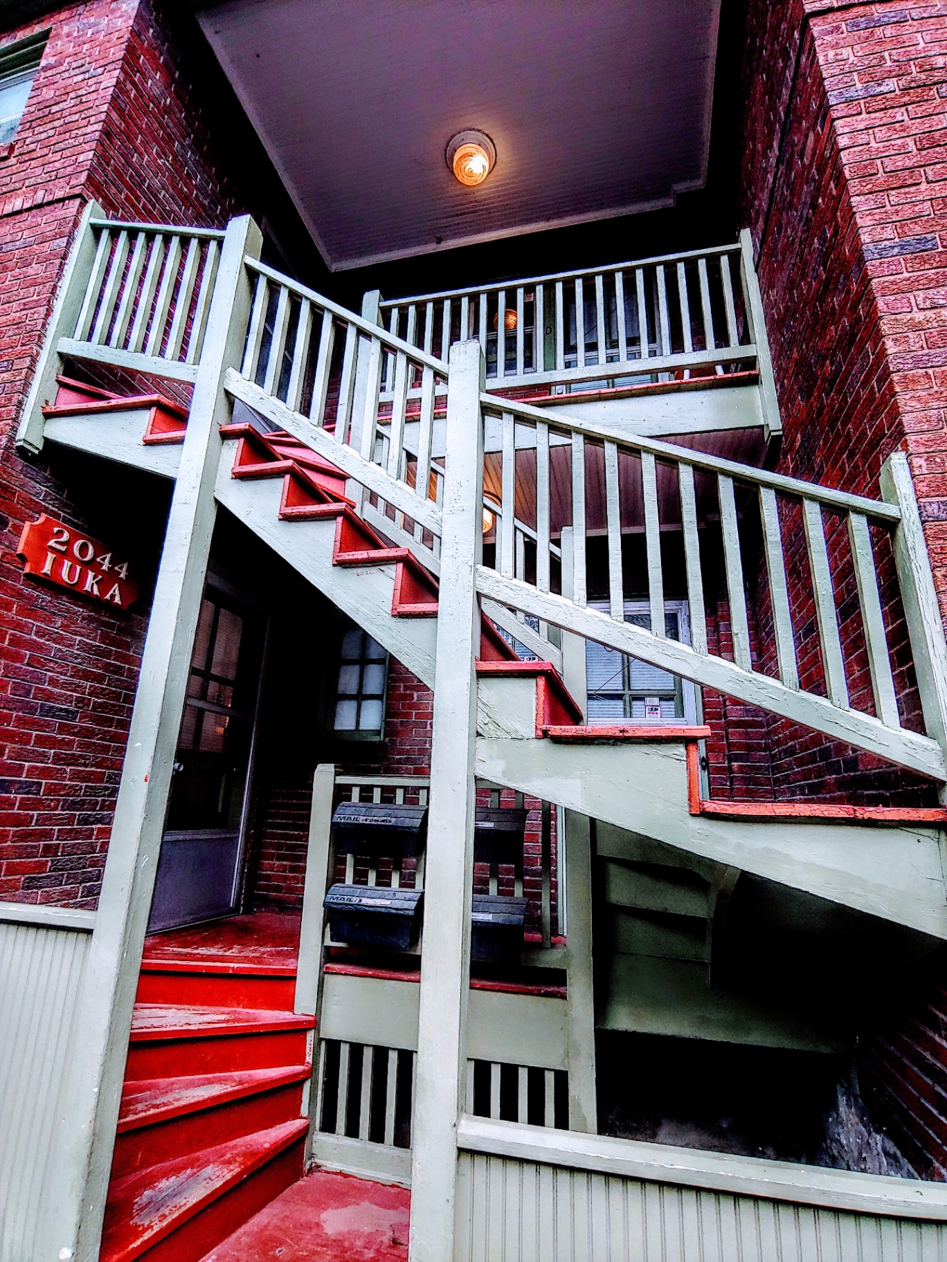 2044 Iuka Ave. exterior red-brick building with signature red-and-green wood staircase to Unit D