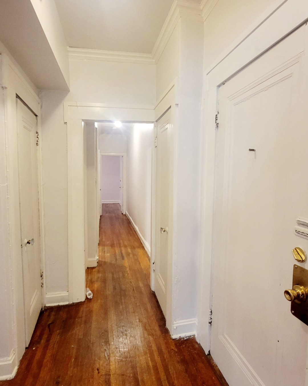 Unit A front hallway with hardwood floors and doors leading to bedrooms and bath