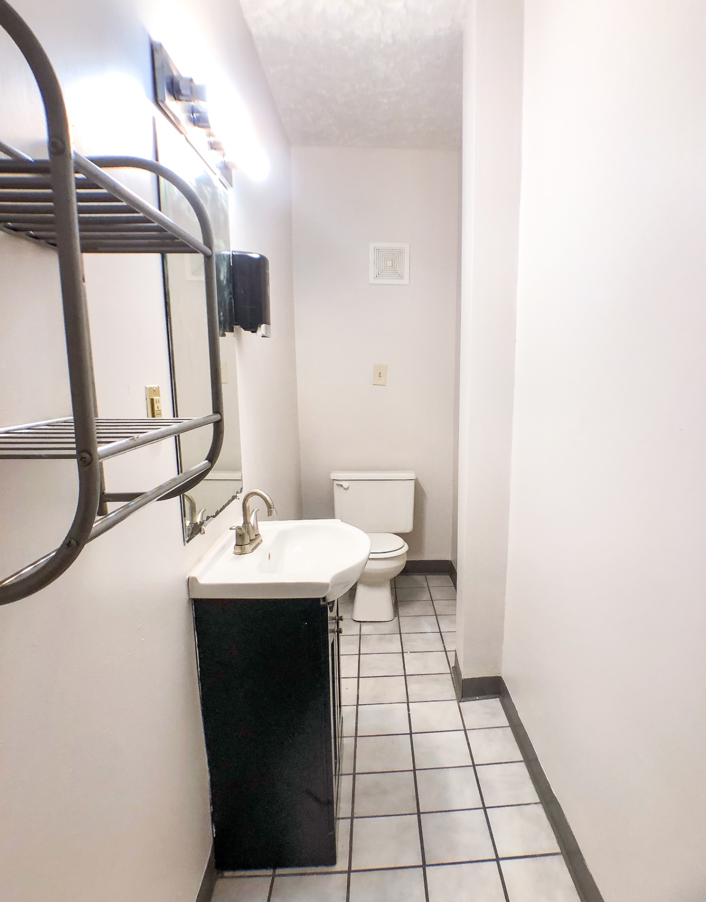 Unit A bathroom with tiled floor, pedestal-style sink and vanity