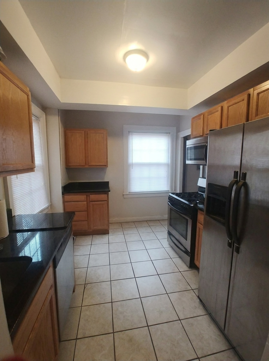 Unit C kitchen with black countertops, stainless steel appliances, and tile floor