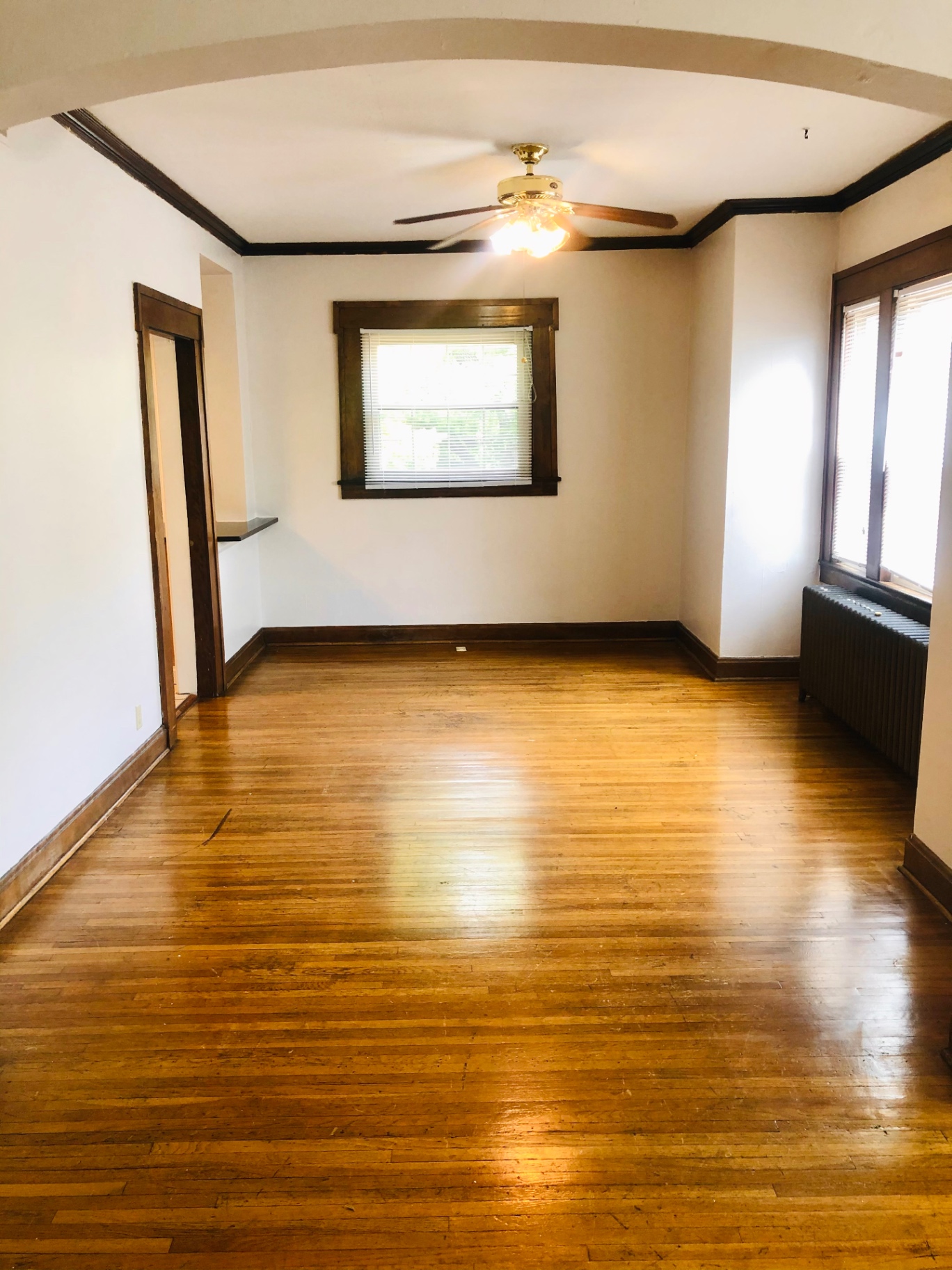 Unit L living room with hardwood floors, ceiling fan, and abundant natural light