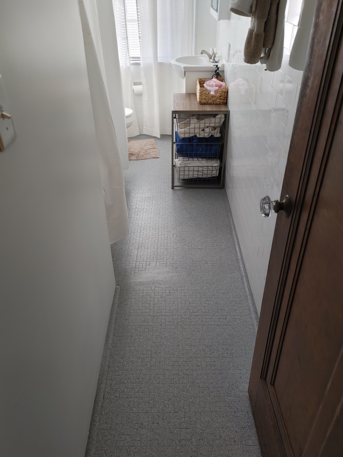 Unit G bathroom with mosaic tile floor and glass-knob wood door