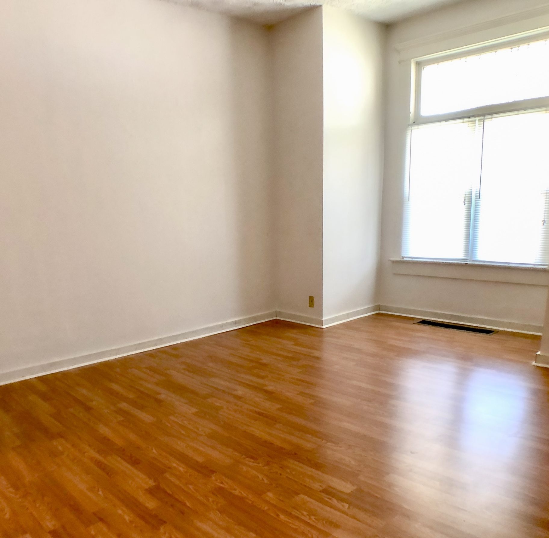 Unit A bedroom with hardwood floors and bright corner window