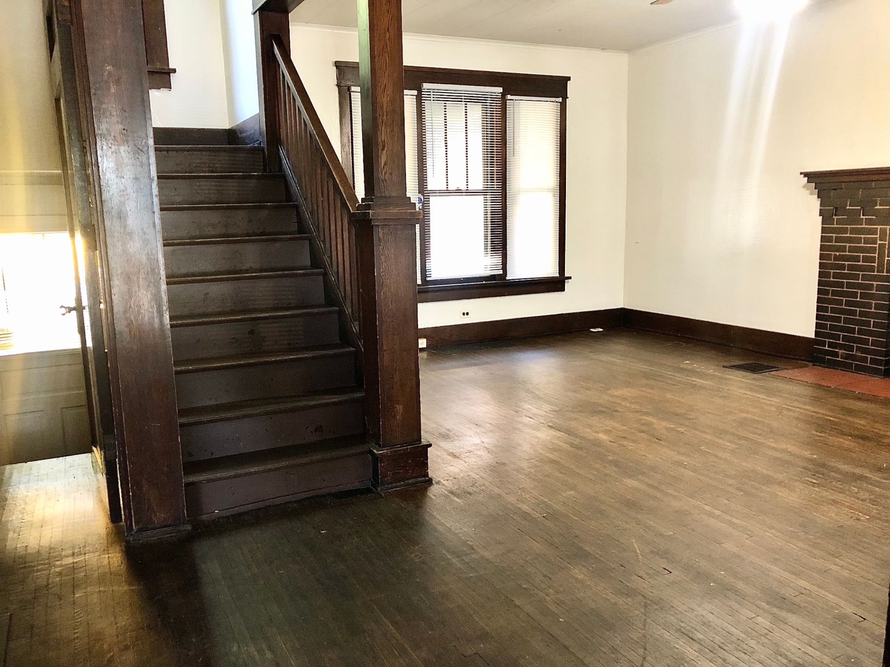2015 Summit St. entry with original dark wood staircase, brick fireplace, and hardwood floors