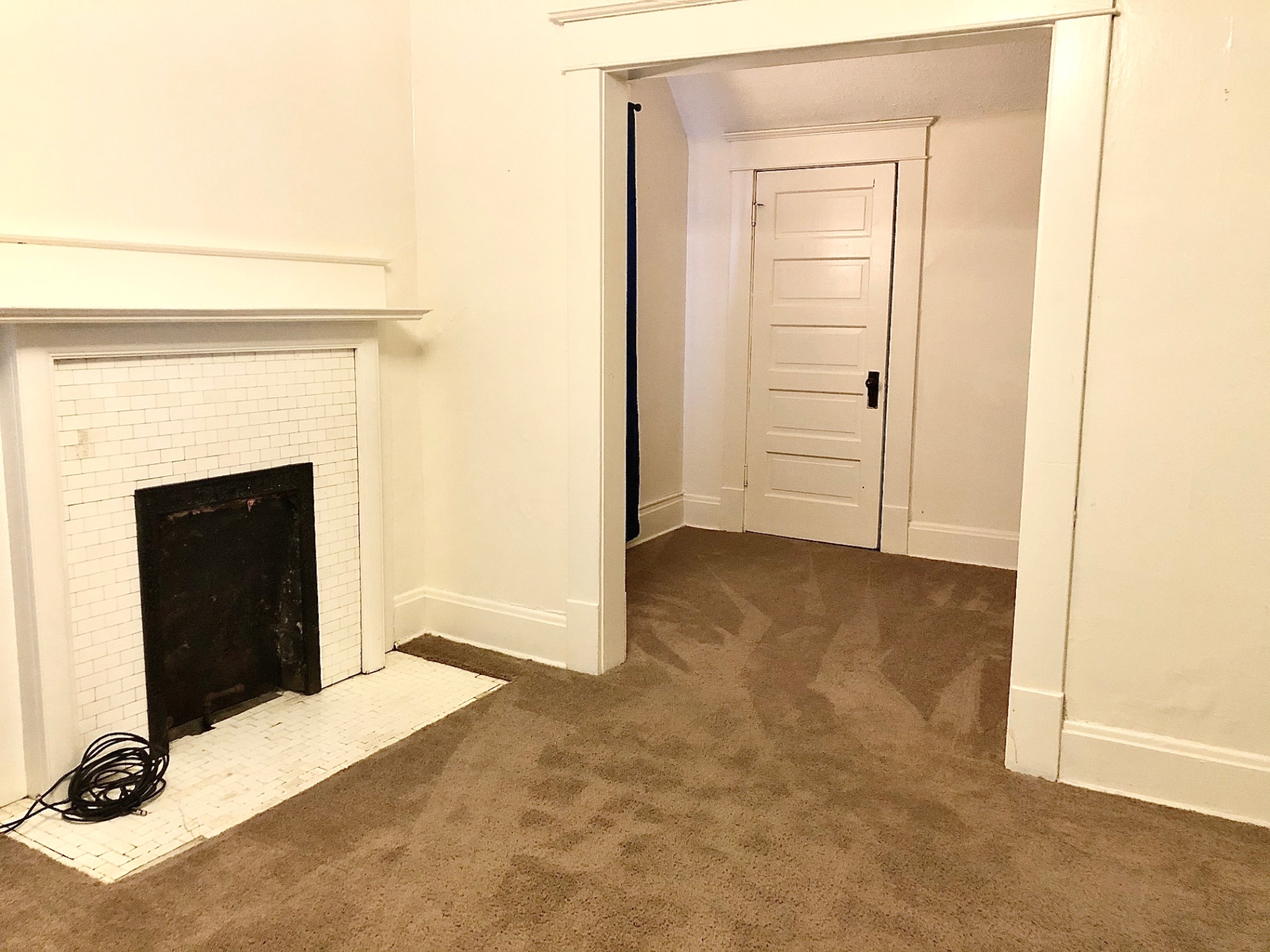 2015 Summit St. carpeted room with white tile fireplace and doorway to adjoining space