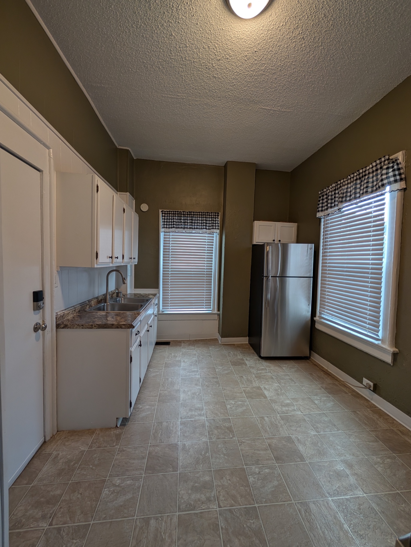 3338 Chestnut Downstairs eat-in kitchen with white cabinets, tile floor and stainless fridge