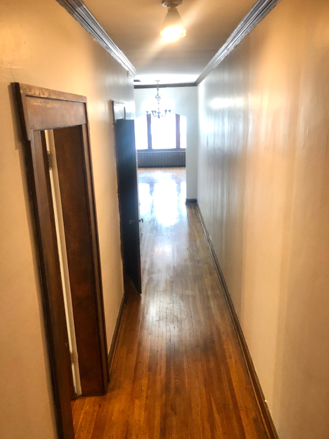 Unit L hallway with hardwood floors leading to bright living area