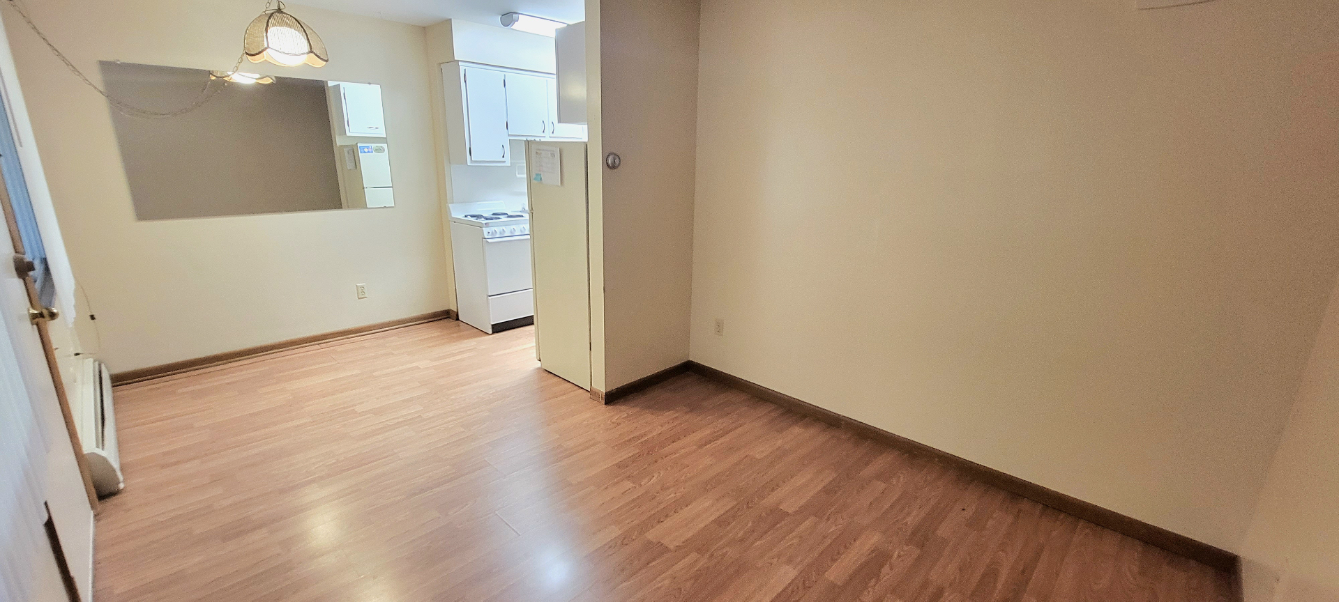 2040 Iuka Ave. 3A wide living and dining area with laminate flooring and kitchen beyond