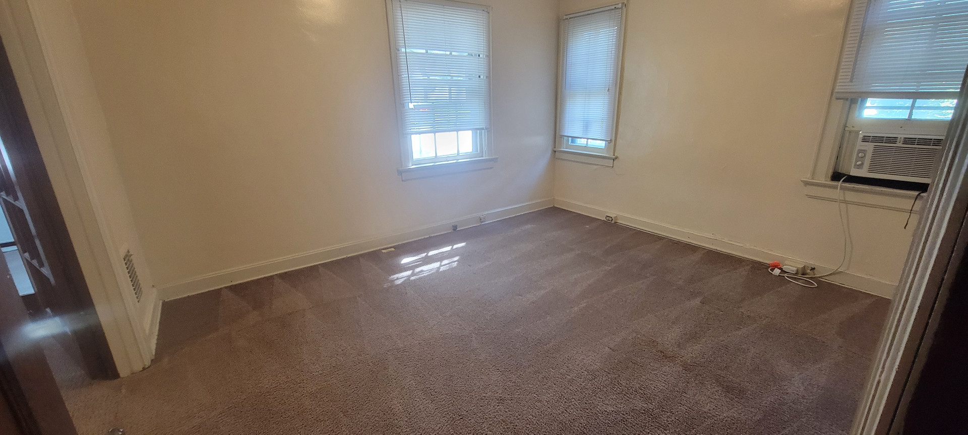 2054 Iuka Ave. A bedroom with three windows, window AC, and fresh carpet