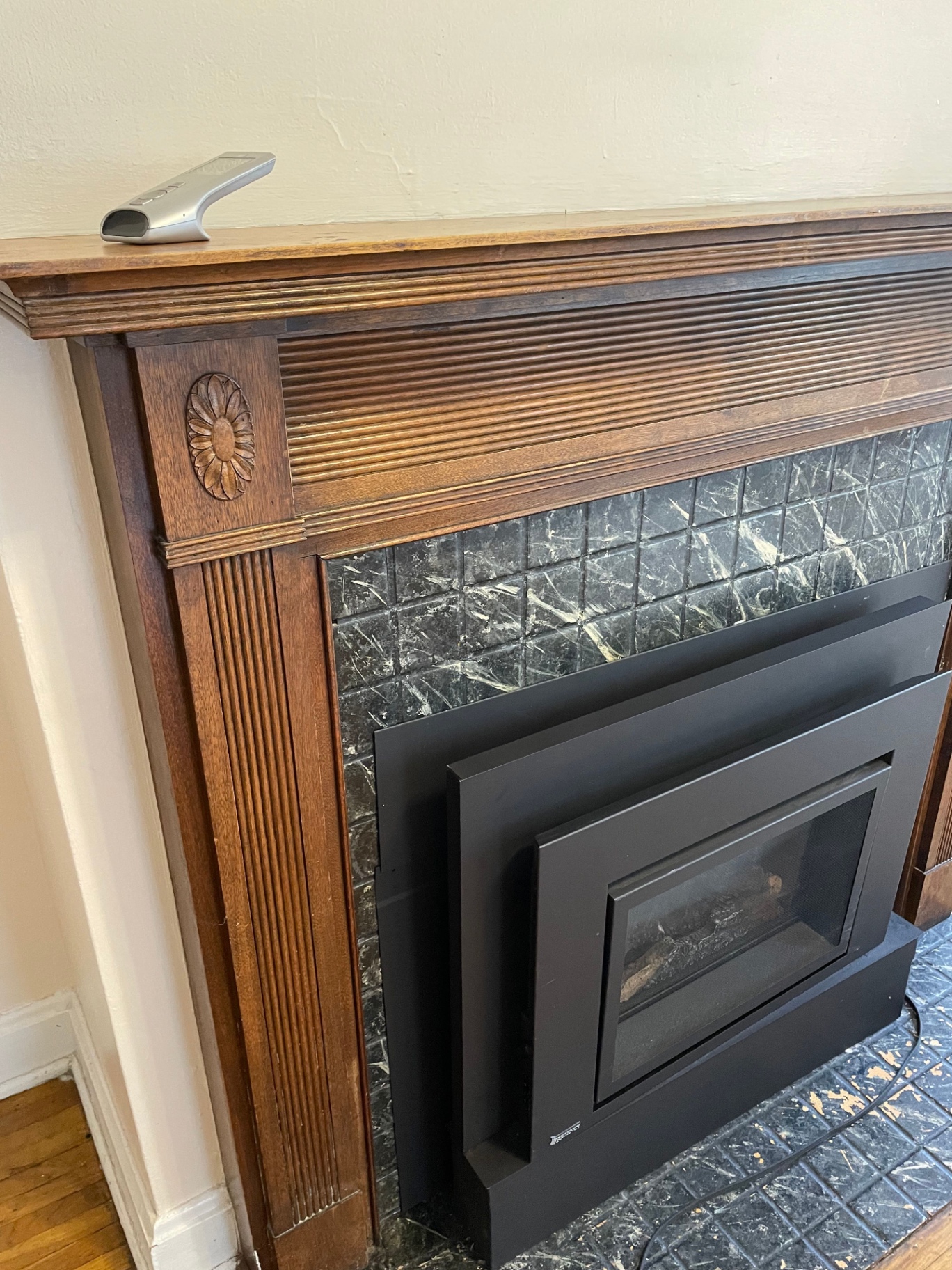 Unit E fireplace detail with wood mantel and marble tile