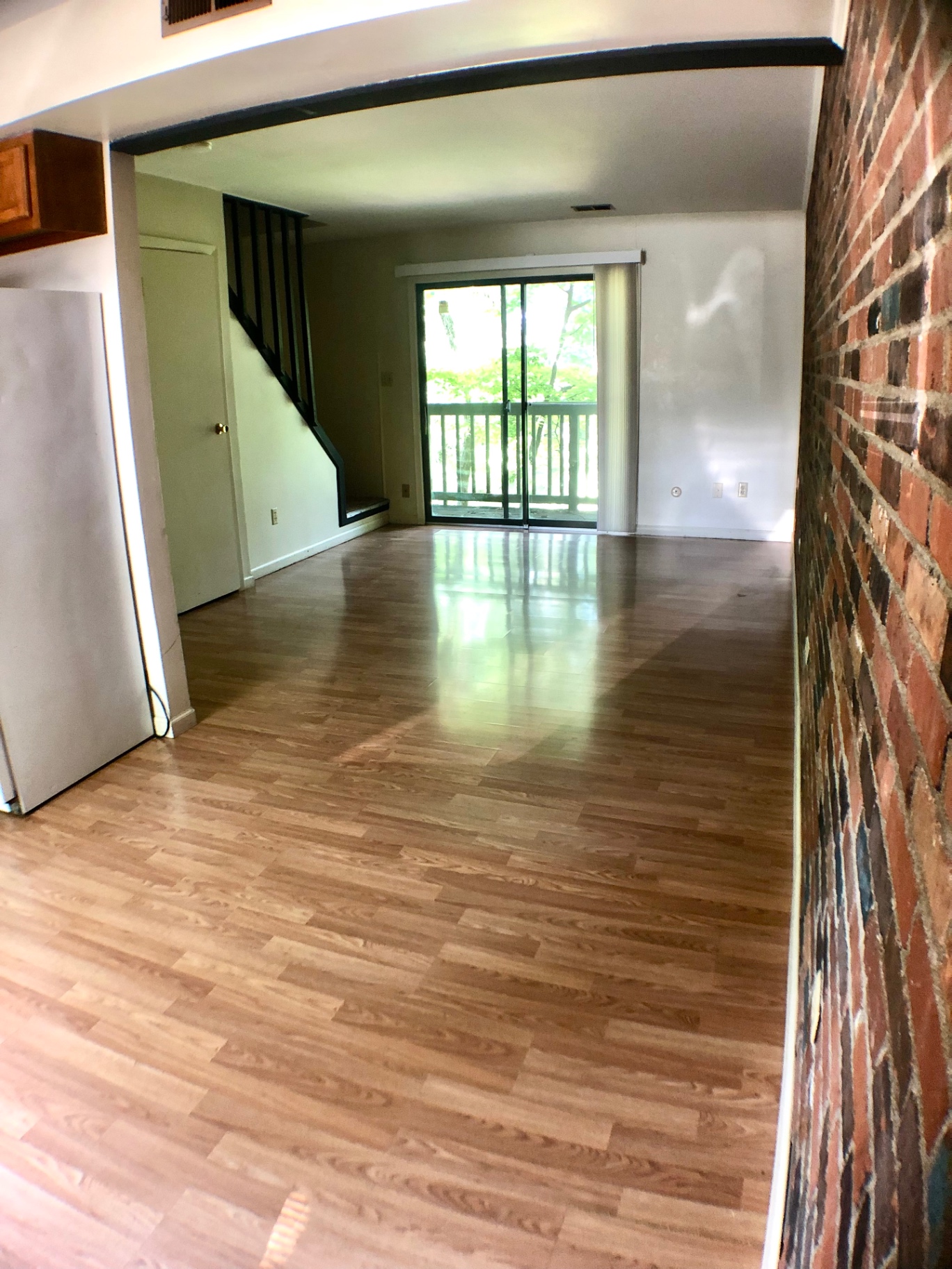 2018 Iuka Ave. long living space with exposed brick wall, wood-look floors, and sliding doors to the balcony
