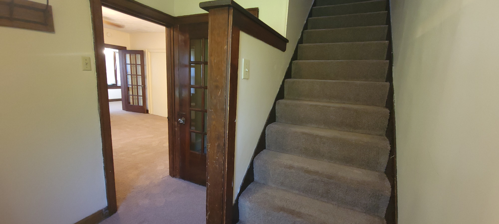 2054 Iuka Ave. C carpeted staircase leading to the second floor with original wood newel post