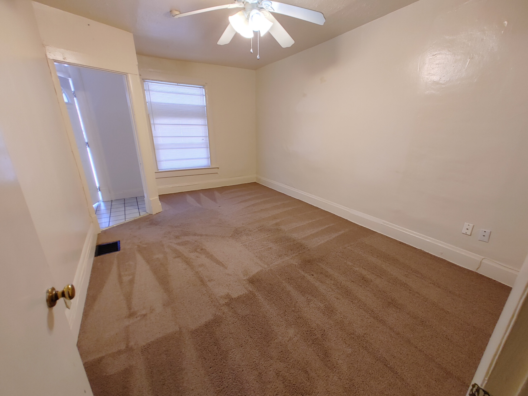 Rear unit main-floor bedroom with ceiling fan, bright window and fresh carpet