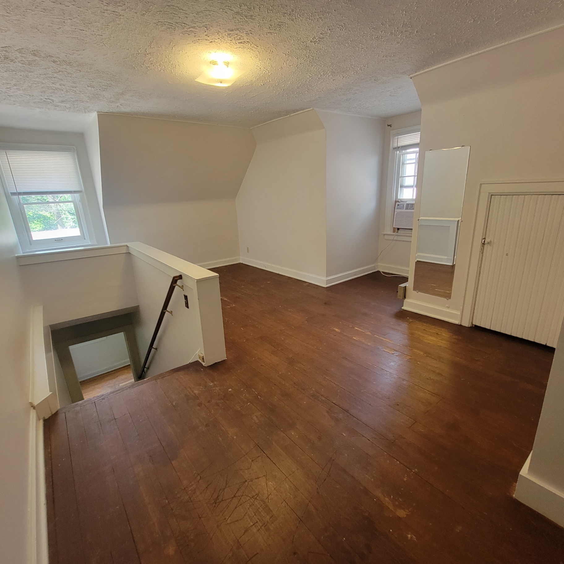 2048 Iuka Ave. C upstairs bedroom with hardwood floors, window A/C, and closet