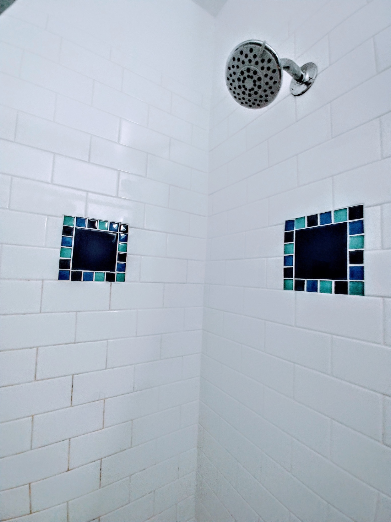 Unit L shower with white subway tile and decorative blue mosaic accents