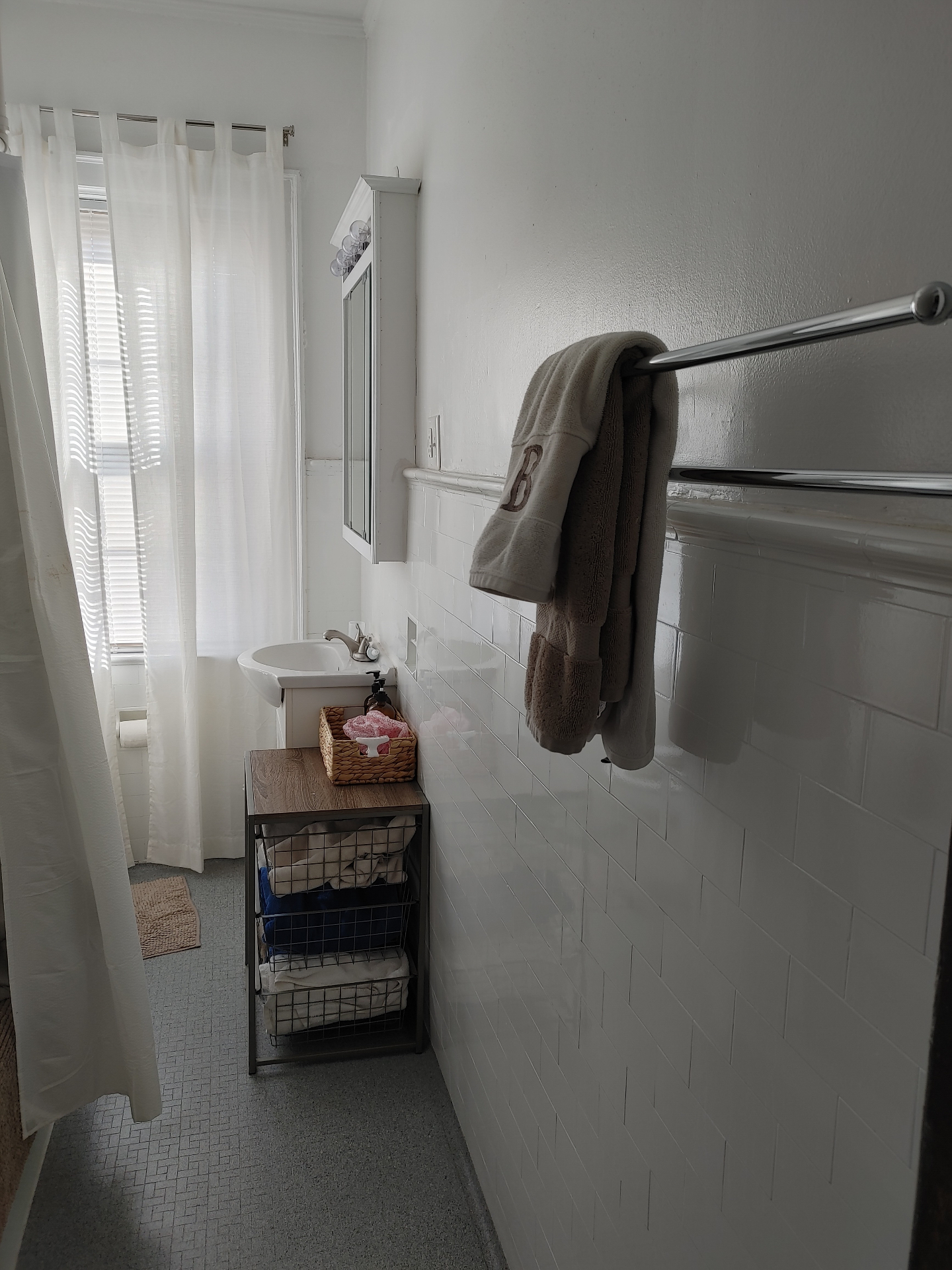 Unit G bathroom with pedestal sink, subway tile wainscoting, and linen storage
