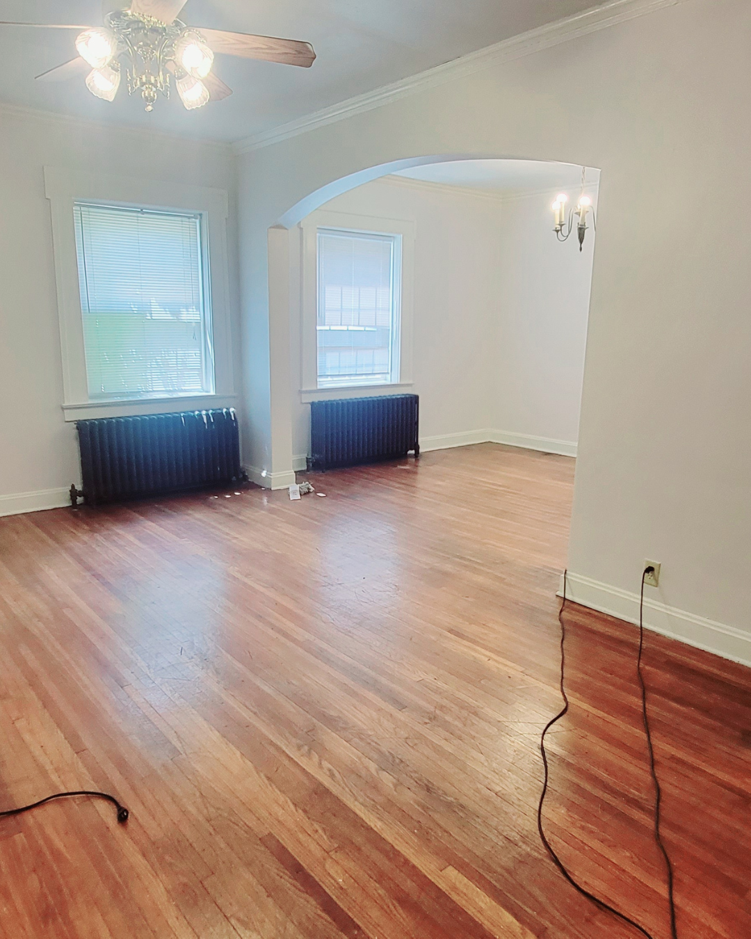 Unit A bright living room with radiators, tall windows, and hardwood floors