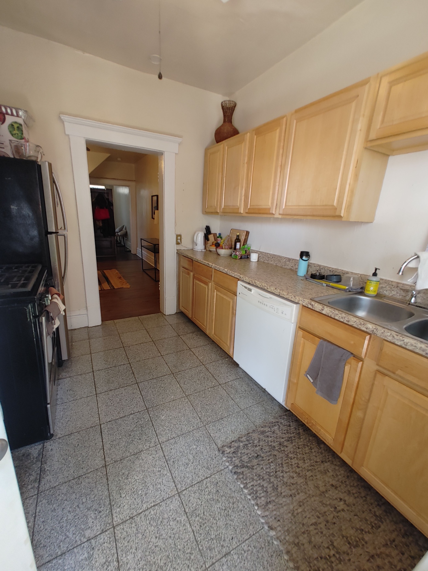 121 W 9th wide galley kitchen with long counters, dishwasher, and view toward hallway