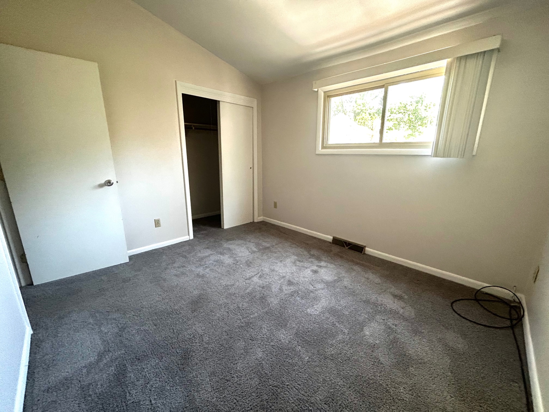 2011 Summit St. Unit E first bedroom with window, open closet, and gray carpet