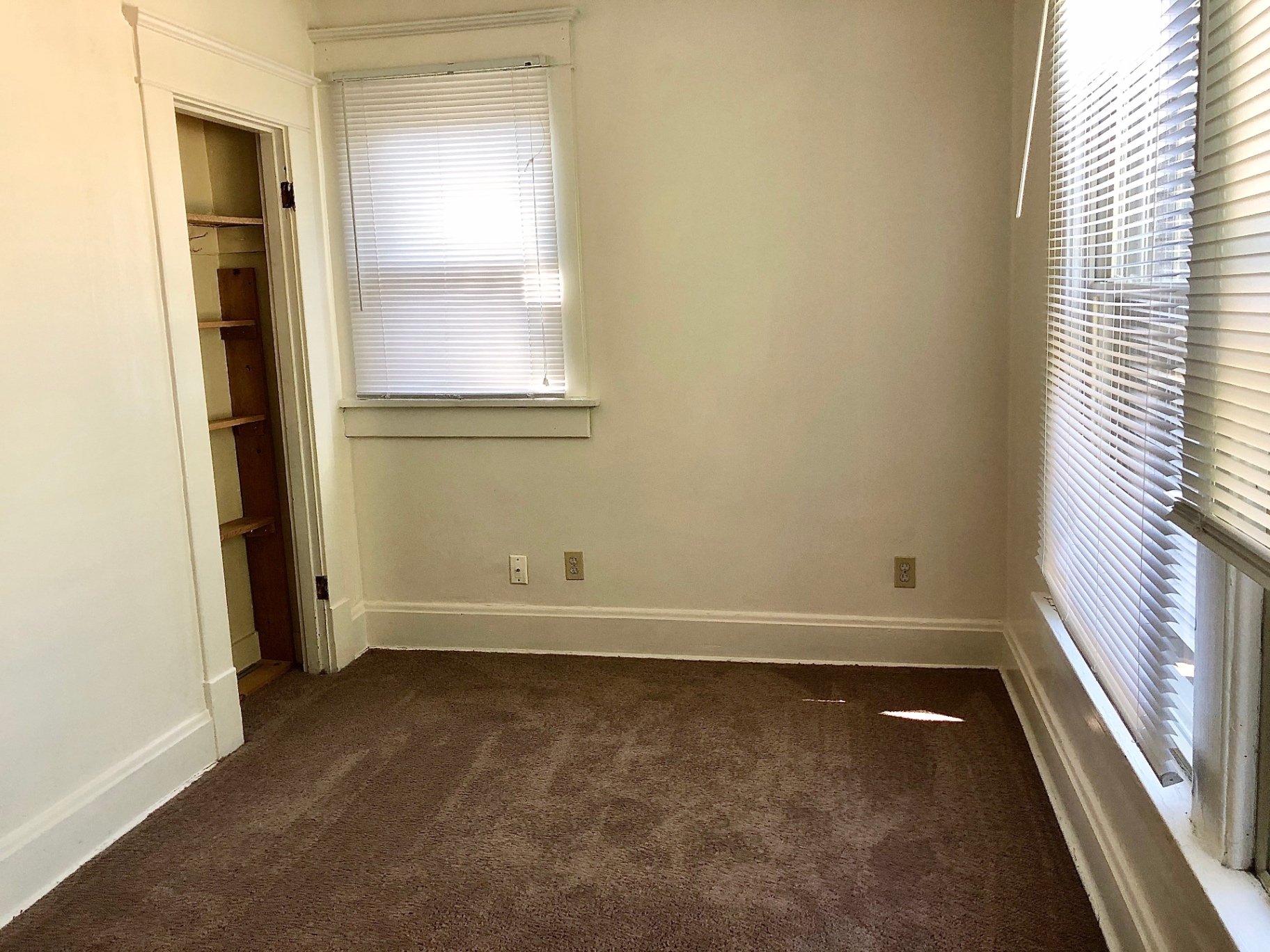 2015 Summit St. bright carpeted bedroom with two windows, blinds, and closet