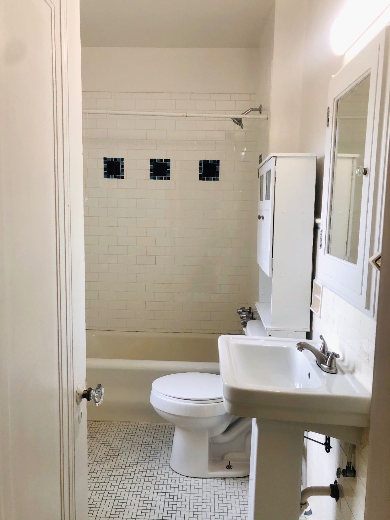 Unit L bathroom with classic subway tile, tub/shower, and pedestal sink