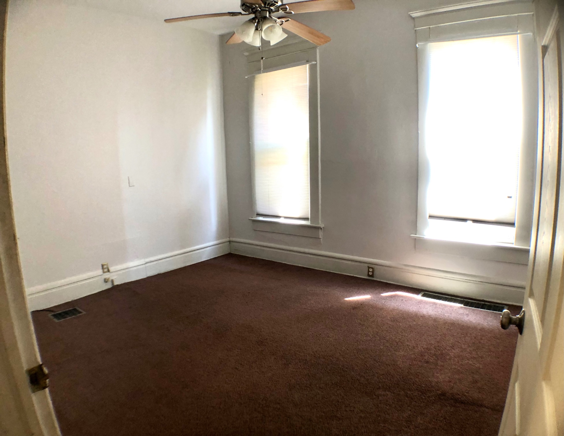 Unit A bedroom with ceiling fan, two bright windows and fresh paint