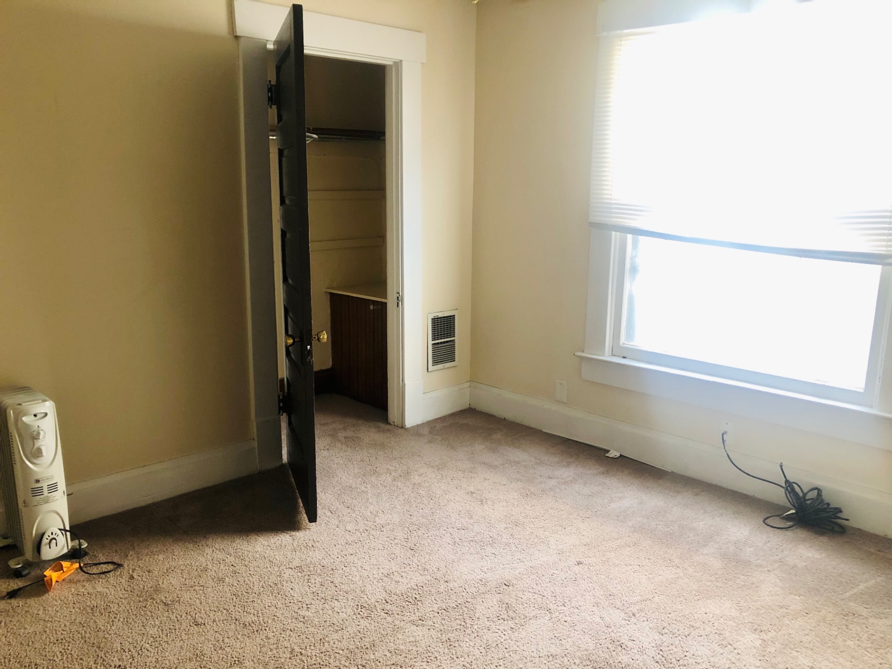 91½ E Woodruff Ave. carpeted bedroom with tall window, closet, and dark original door